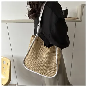 Dettaglio della borsa tote in paglia intrecciata con spalline bianche indossata