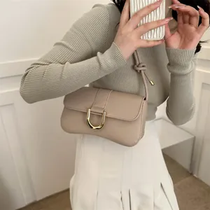 Minimalist beige underarm bag with gold metal clasp and adjustable knotted shoulder strap