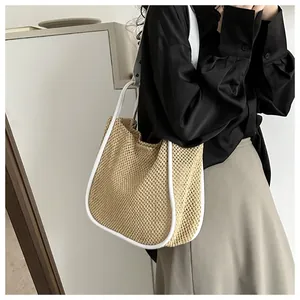 Dettaglio di borsa tote in paglia intrecciata con finiture in pelle bianca e tracolla