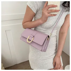 Detail of a purple baguette bag with gold U-shaped metal buckle worn by a model
