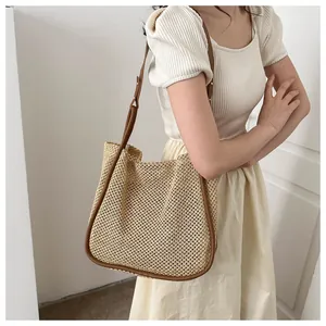 Dettaglio della borsa tote intrecciata con tracolla in pelle marrone e superficie beige