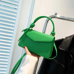 Green woven corduroy textured handbag with unique top handle and golden hardware finish