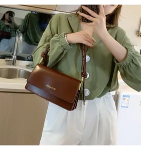 Mirror selfie showing the dark brown PU leather baguette bag with a knotted strap detail