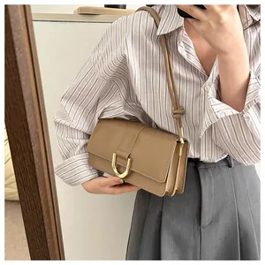 Detail of khaki baguette bag with golden horseshoe buckle and accordion side gussets