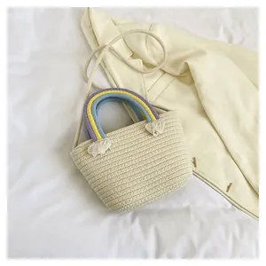 Detailaufnahme einer cremefarbenen geflochtenen Tasche mit Regenbogen griff und Quasten