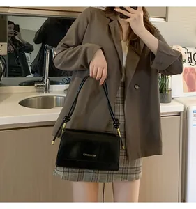 Close-up of black leather baguette bag with gold hardware and unique knot handle detail