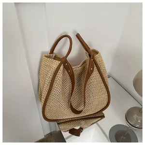 Dettaglio della borsa tote in paglia intrecciata con manici in pelle marrone e rivetti