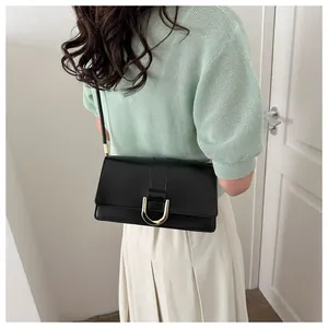 Detail of a black leather French baguette bag showing the golden U-shaped metal buckle