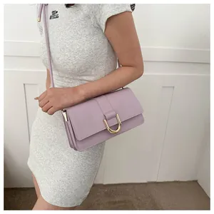 Detail of light purple leather crossbody bag with gold U-shaped buckle and pleated side