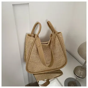 Dettaglio della borsa tote in paglia intrecciata con finiture in pelle kaki e manici