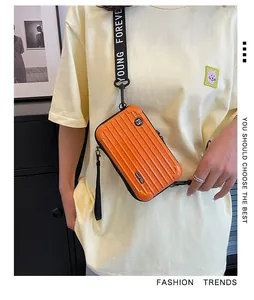 Macro shot of orange hardshell suitcase crossbody bag with Young Forever wide strap