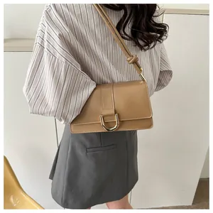 Detail of caramel leather baguette bag showing golden D-buckle and knotted shoulder strap