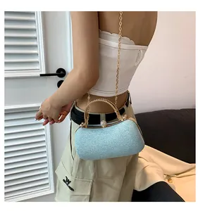 Close-up of light blue glitter clutch bag with gold chain strap worn by a female model