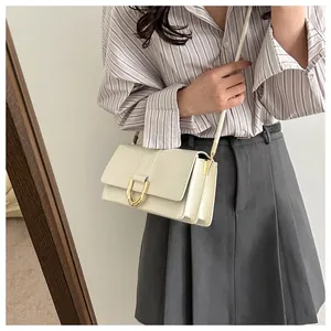 Chic beige baguette bag with golden U-shaped hardware shown worn by a model