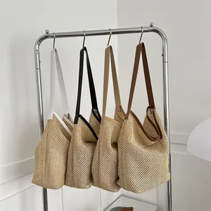 Grands sacs cabas tissés en blanc, noir et marron présentés sur des cintres en acier