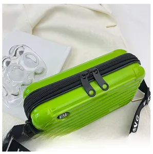 Detail of a bright green suitcase-style crossbody bag with smooth black zippers