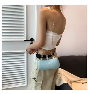Light blue textured crossbody bag with gold chain strap and metal handle on a model