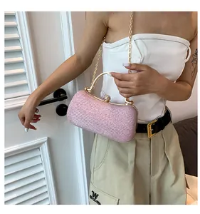 Detail of pink glitter evening bag with gold circular handle and diamond clasp on a model