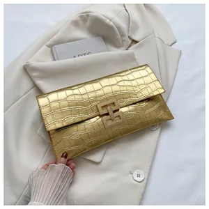 Close-up of gold envelope clutch bag featuring crocodile texture and metallic lock buckle