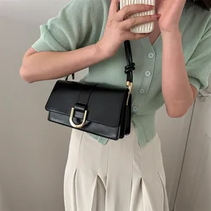 French style black leather baguette bag with gold horseshoe buckle and knot strap detail