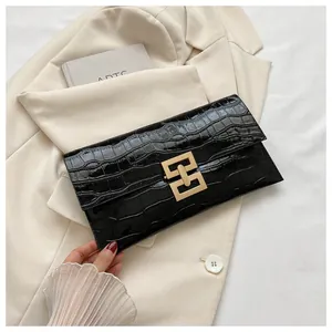 Macro shot of black crocodile pattern envelope clutch with golden geometric clasp