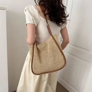 Borsa tote in paglia minimalista con cinturini in pelle marrone indossata da una modella