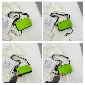 Detailed views of a bright green mini suitcase bag with Forever Young wide strap
