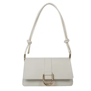 Elegant cream leather baguette bag with golden D-ring buckle and braided knot strap