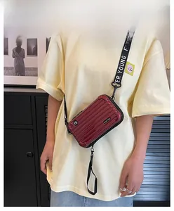 Red mini suitcase crossbody bag with vertical stripe design and wide nylon shoulder strap