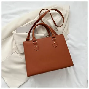 Detail of brown Saffiano faux leather tote bag with gold hardware and adjustable strap
