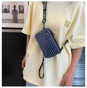 Detail of dark blue mini suitcase crossbody bag with white lettered wide strap