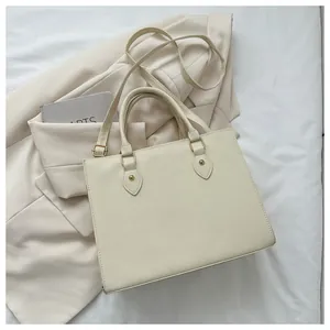 Detail of cream white tote bag with crosshatch texture and light gold hardware