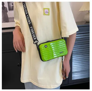 Vibrant lime green hardshell mini suitcase crossbody bag with lettered strap on model