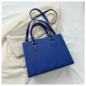 Detail view of electric blue tote bag with saffiano texture and gold hardware