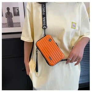 Detail of a bright orange hardshell suitcase crossbody bag with Young Forever strap