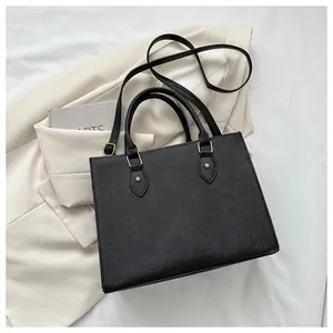 Detailed macro view of black faux leather tote with golden hardware and adjustable strap