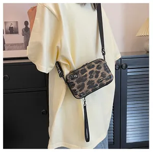 Mini leopard print hard shell trunk bag worn as crossbody with branded woven strap