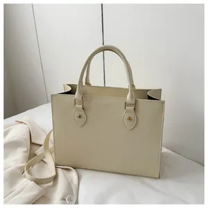 Detailed close-up of cream saffiano leather tote bag with gold hardware and shoulder strap