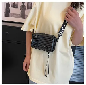 Detail of a black hardshell luggage-style crossbody bag with Forever Young strap
