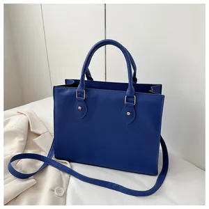 Detail of royal blue tote bag featuring fine cross-grain texture and gold metal rivets