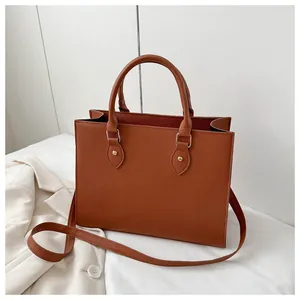 Detail of dark brown tote bag with cross-grain texture, leaf-shaped leather and gold hardware