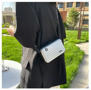 Detail view of silver mini suitcase crossbody bag with Forever Young strap on a model