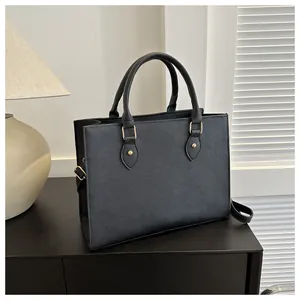 Close-up of black Saffiano tote bag with round handles and gold stud hardware details