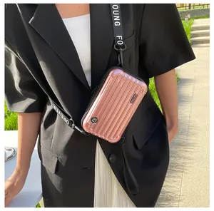 Outdoor model shot of rose gold mini suitcase crossbody bag with Forever Young strap