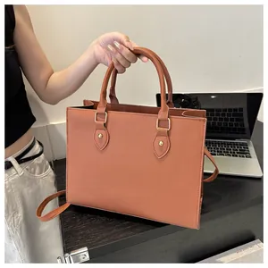 Detail of a brown tote bag featuring cross-grain faux leather and gold hardware accents