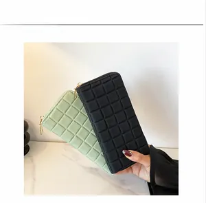 Close-up of long zip-around wallets with quilted square pattern in black and green colors