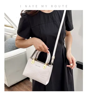 White crocodile pattern PU handbag with woven handle and gold hardware on a sofa