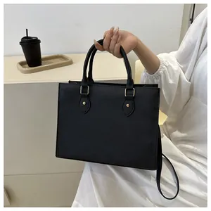 Detail of black tote bag with textured faux leather and elegant gold hardware accents