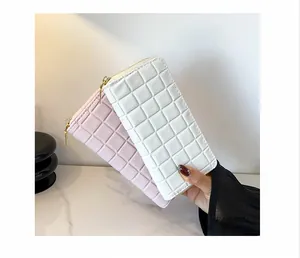 Detail of pink and white quilted leather wallets with golden zippers on marble background