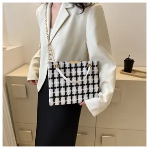 Détail d'un sac à main en tweed noir et blanc classique avec chaîne dorée et bandoulière blanche